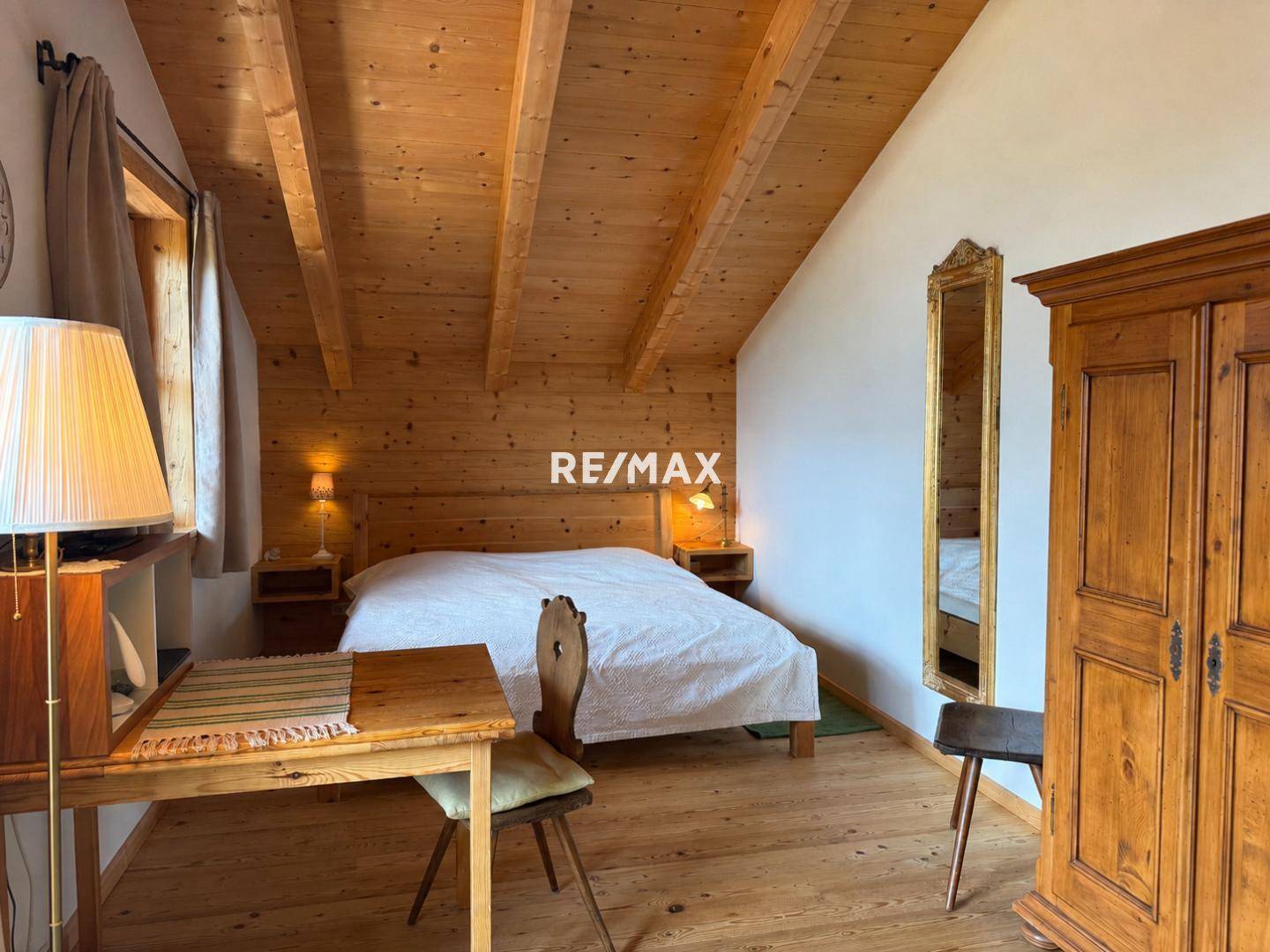 Gemütliches Schlafzimmer mit Holzbalkendecke, traditionellen Holzmöbeln und Holzboden.