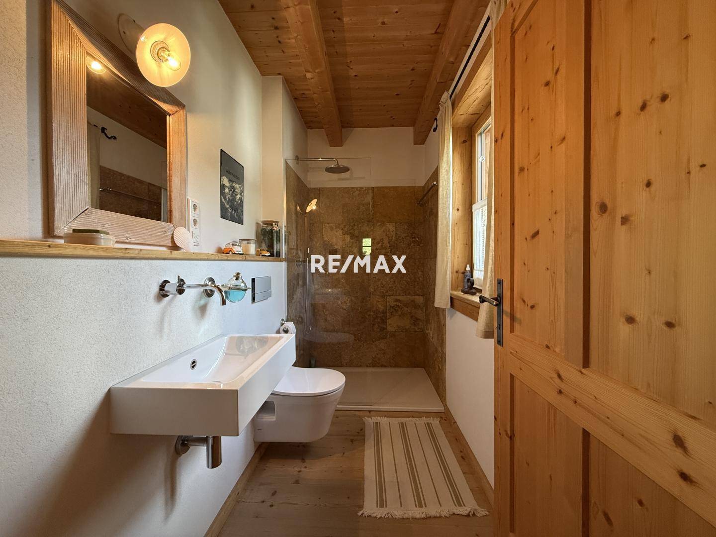 Modernes Badezimmer mit Holzbalkendecke, Duschkabine, Wand-WC und Holzwaschtisch.