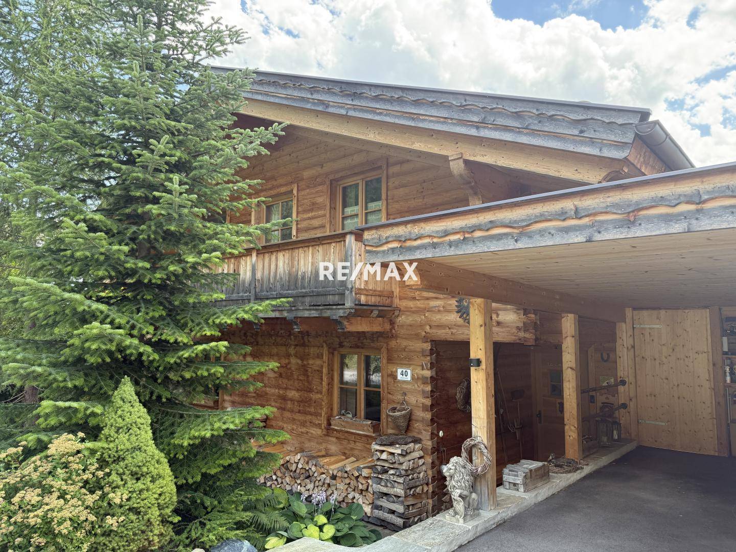 Traditionelles Holzhaus mit Carport, Balkon und umgebender Natur in den Bergen.