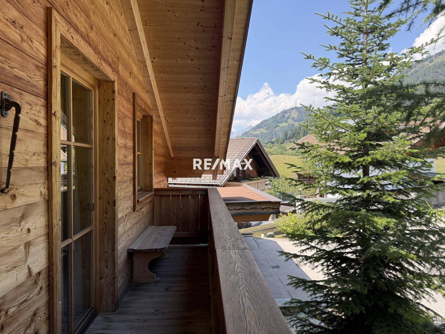 Hölzerner Balkon mit Sitzbank und Blick auf die umliegende Berglandschaft und Natur.