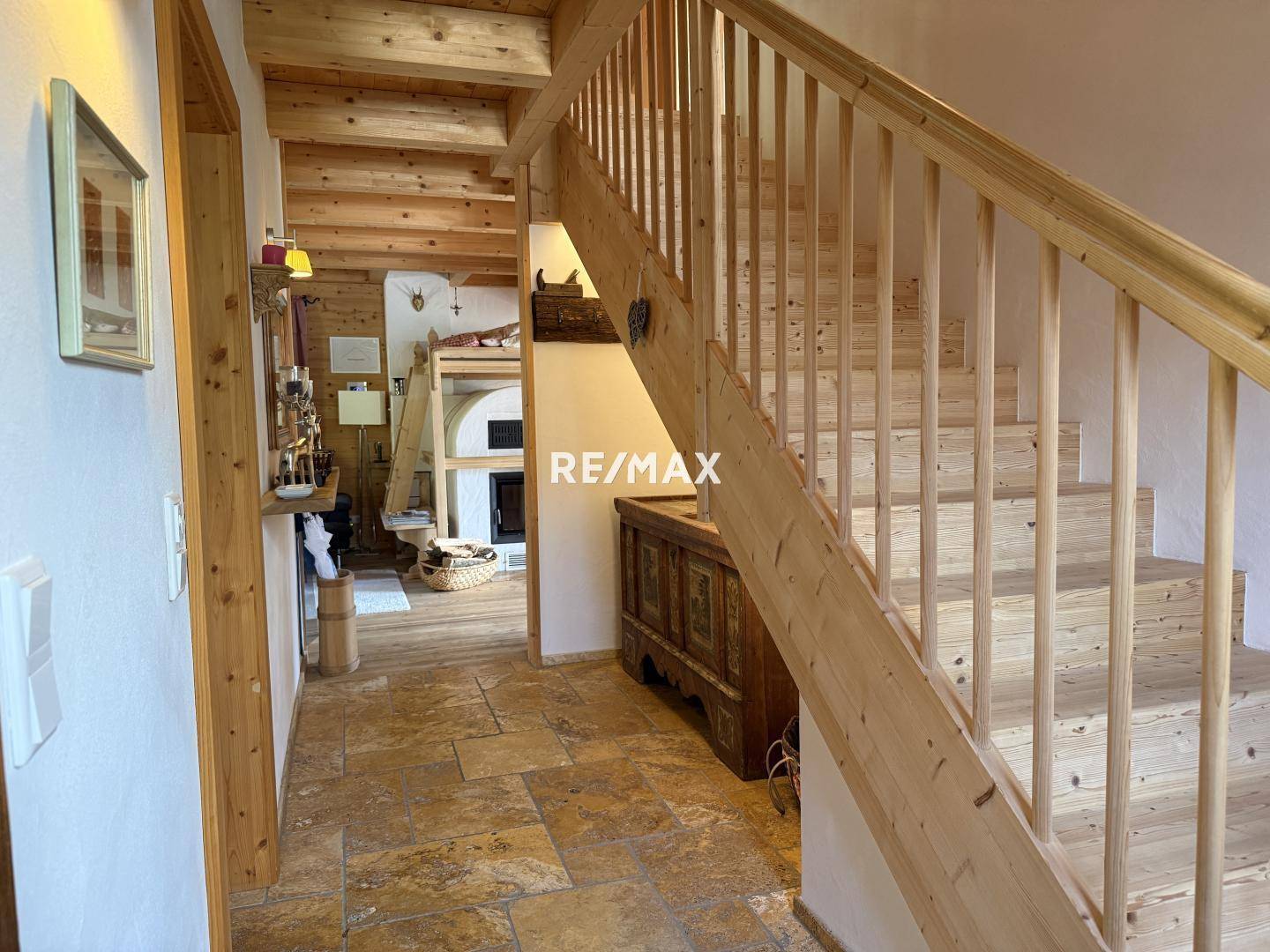 Heller Flur mit Holztreppe und Steinboden, der zu den oberen Etagen des Hauses führt.