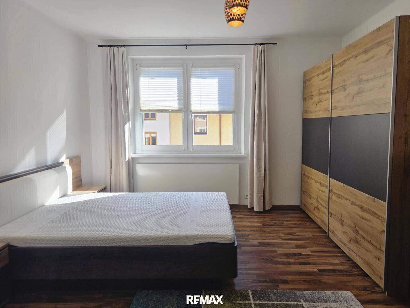 Schlafzimmer mit Doppelbett, großem Kleiderschrank und Laminatboden.