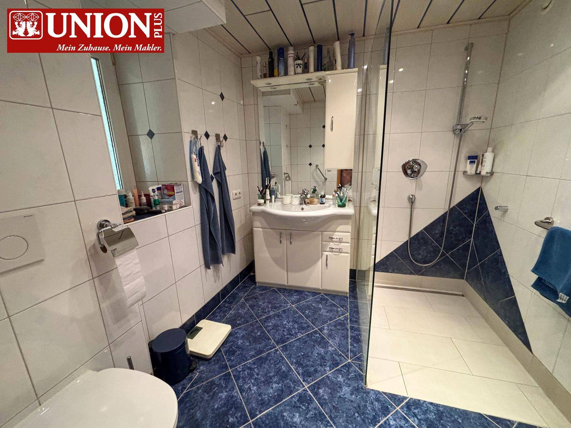 Badezimmer mit blauen Fliesen, Duschkabine und Waschbecken mit Spiegelschrank.