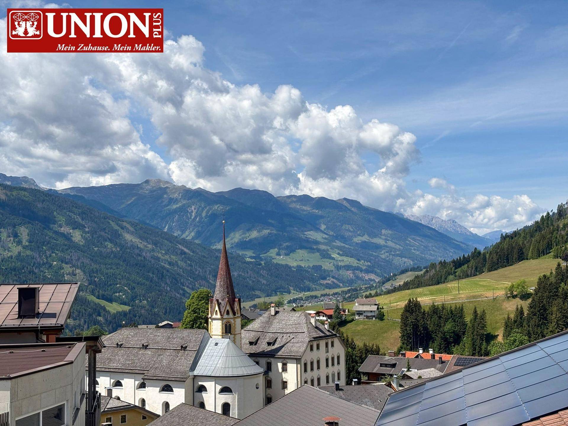 Malerischer Blick auf ein Bergdorf mit Kirche und umliegende Alpenlandschaft.