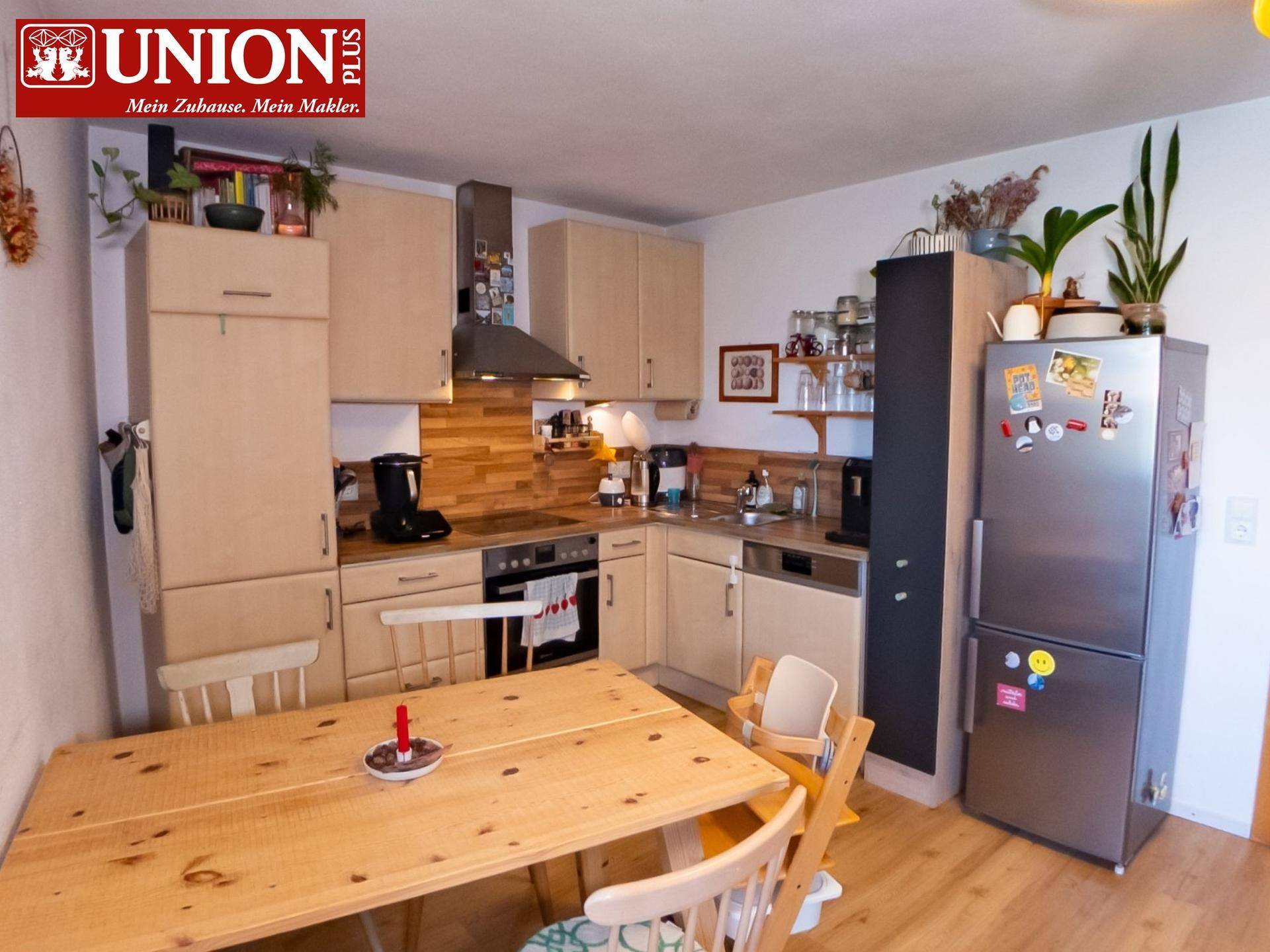 Gemütliche Küche mit hellen Holzfronten, Essbereich und modernen Geräten.