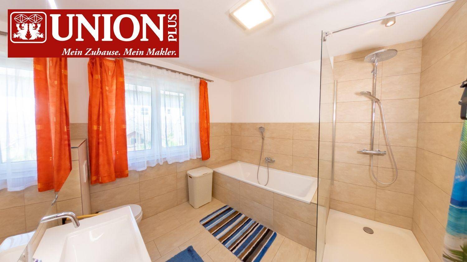 Helles Badezimmer mit Badewanne, separater Dusche und Fenster für Tageslicht.