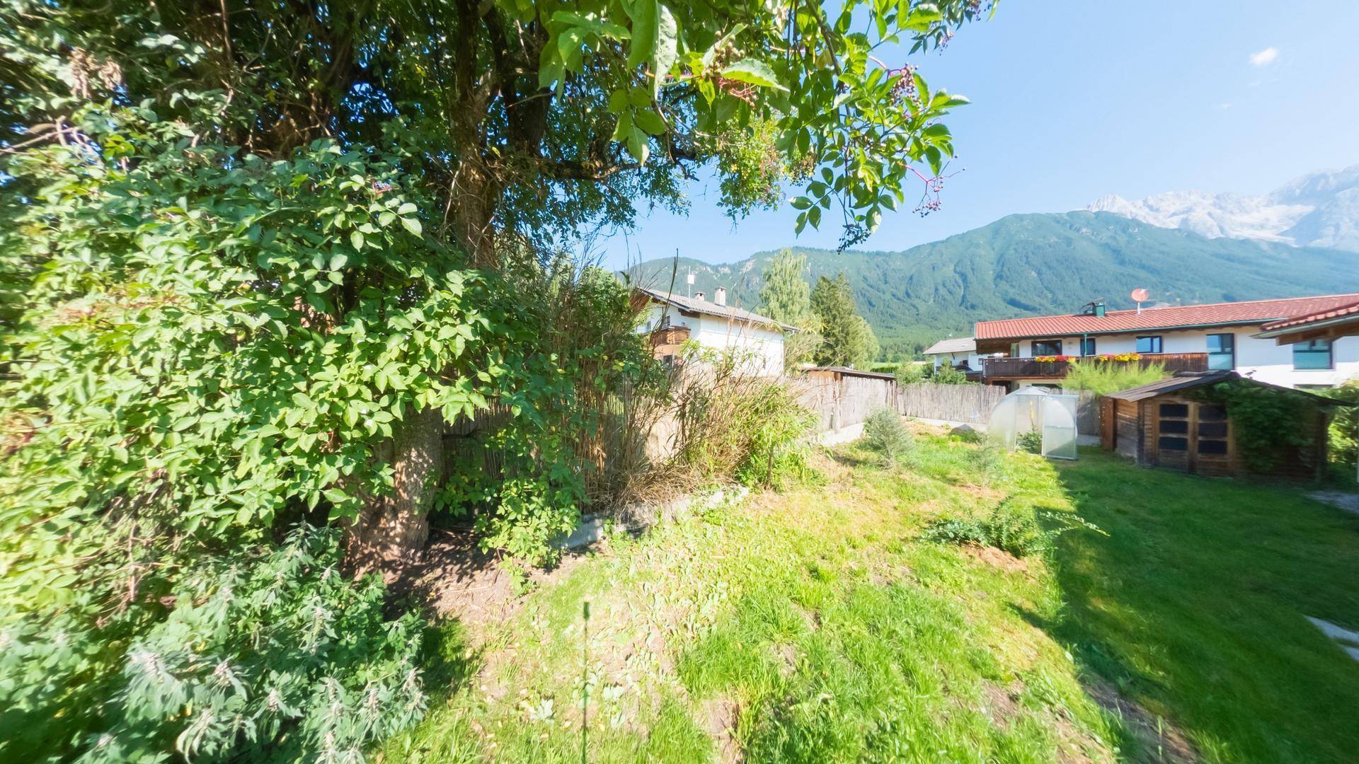 Weitläufiger Gartenbereich mit üppiger Vegetation und Blick auf die umliegende Berglandschaft.