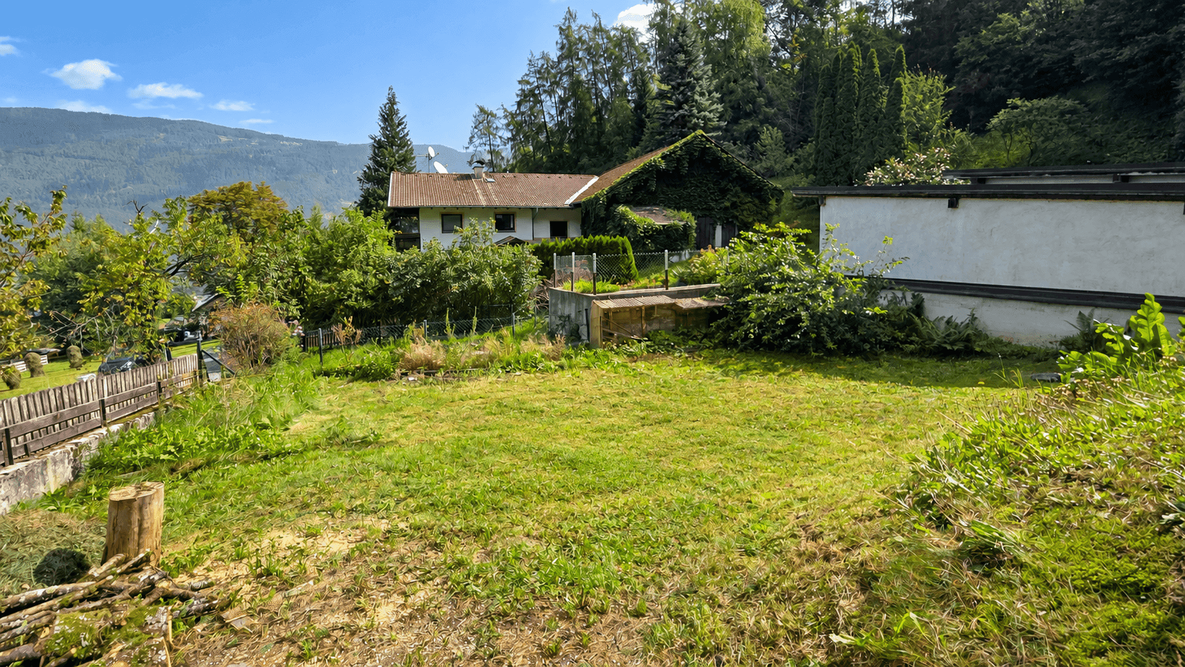 Großer grüner Gartenbereich mit Rasenfläche und Blick auf die umliegende Landschaft.