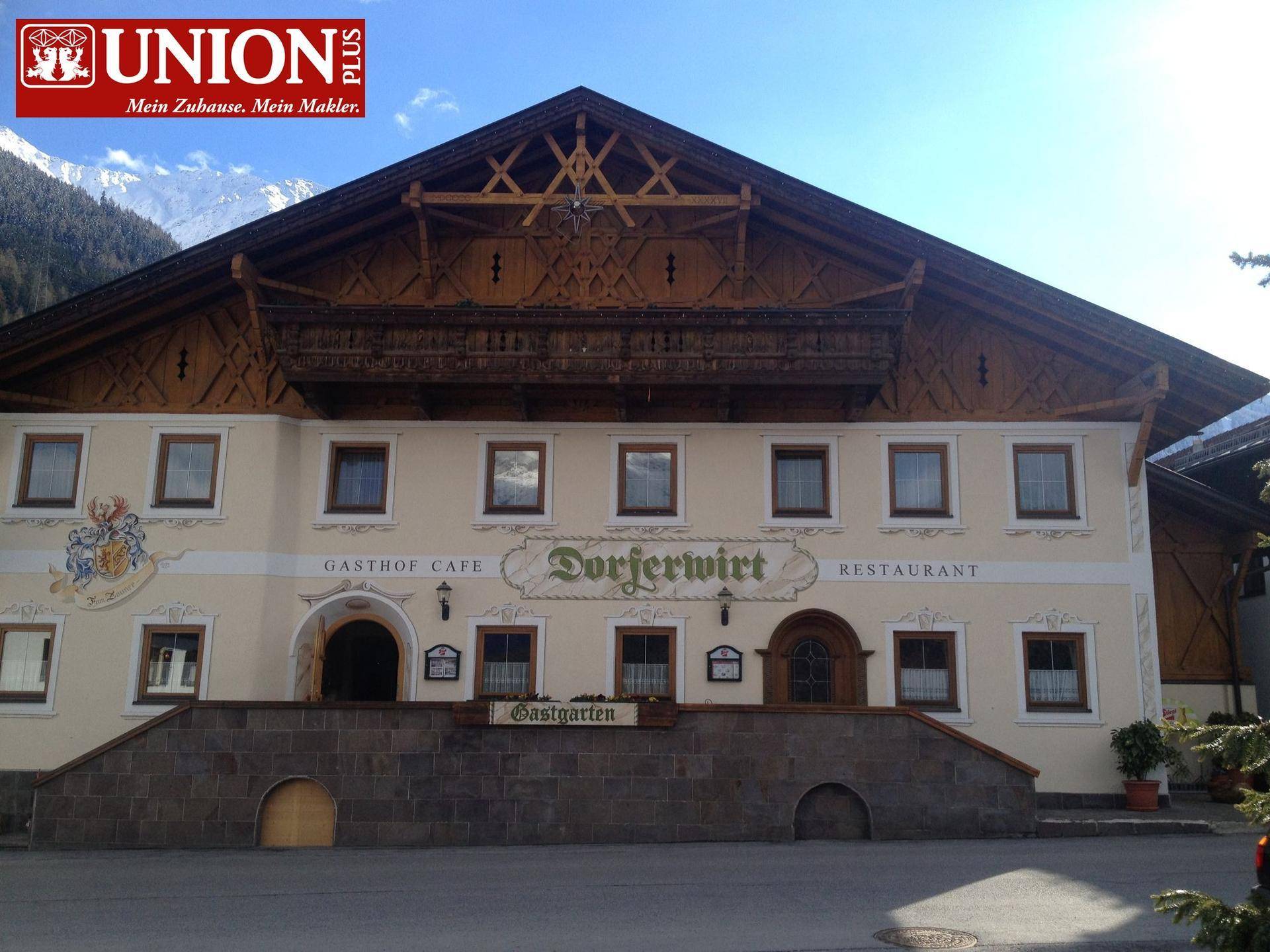 Frontansicht des Gasthofs mit traditioneller Holzfassade und bemalten Details.