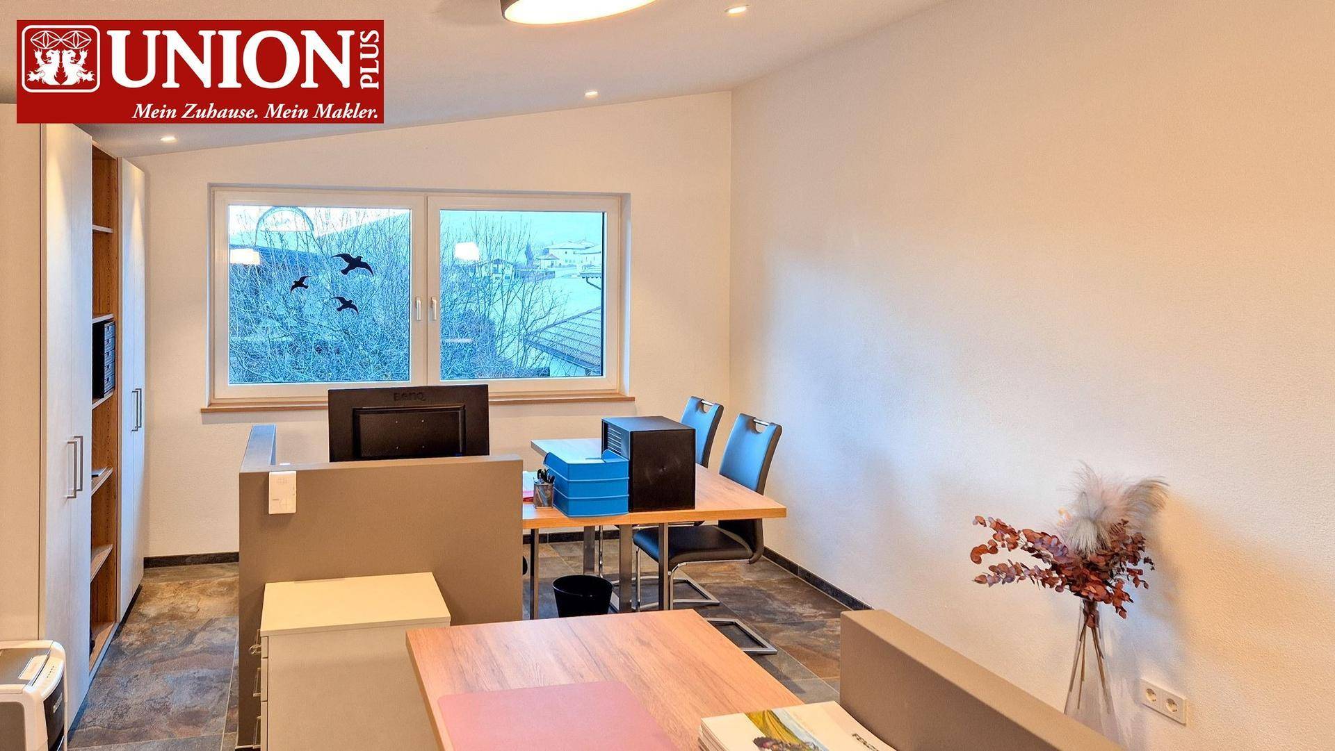 Funktionales Büro mit Schreibtisch, Regalen und Fensterblick, möglicherweise im Dachgeschoss.