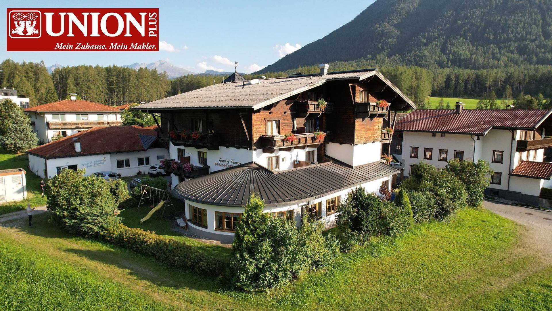 Traditionelles Gebäude im alpinen Stil mit weitläufigem Garten und Bergblick.