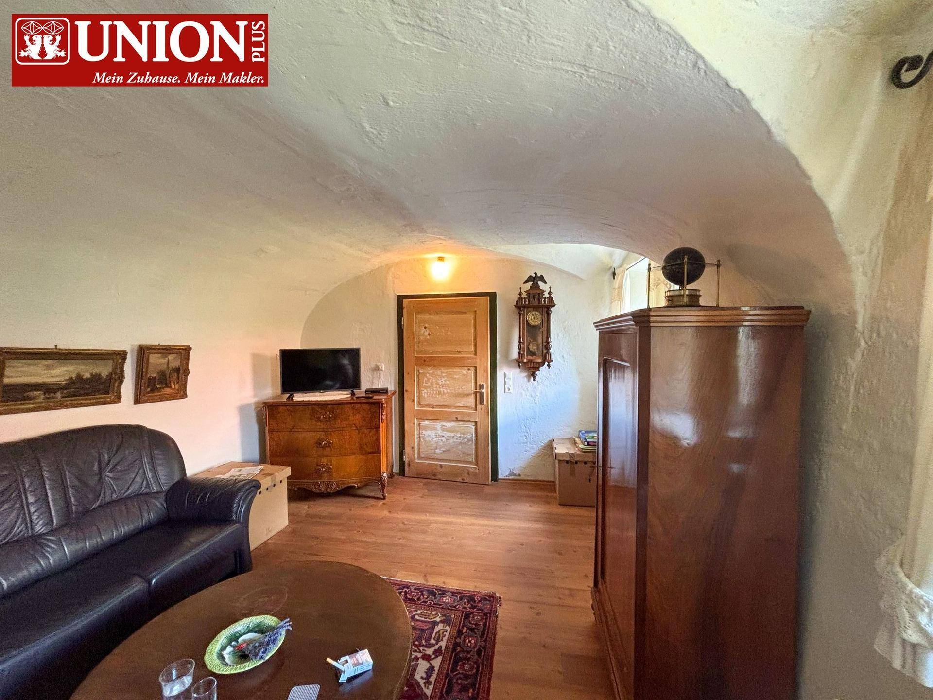 Gemütliches Wohnzimmer mit Gewölbedecke, Holzboden und traditionellen Möbeln.