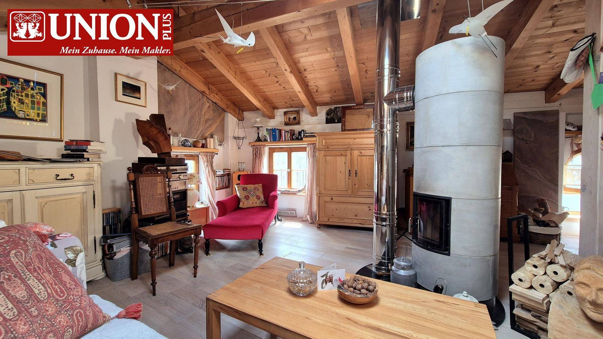 Helles Wohnzimmer mit modernem Kaminofen, Holzbalkendecke und rustikalen Möbeln.
