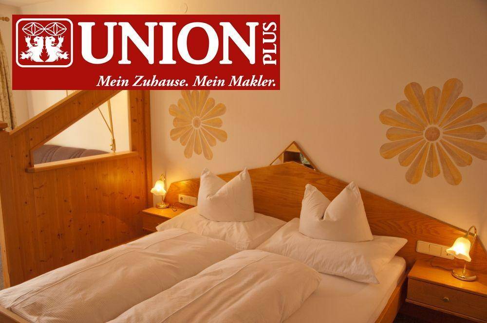 Gemütliches Schlafzimmer mit Holzmöbeln, Doppelbett und traditioneller Wanddekoration in warmen Farben.