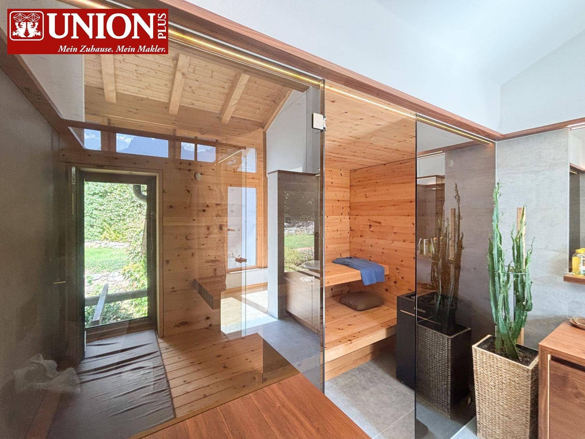 Moderne Sauna mit Glasfront und hellem Holzinterieur, bietet direkten Zugang zum Garten.