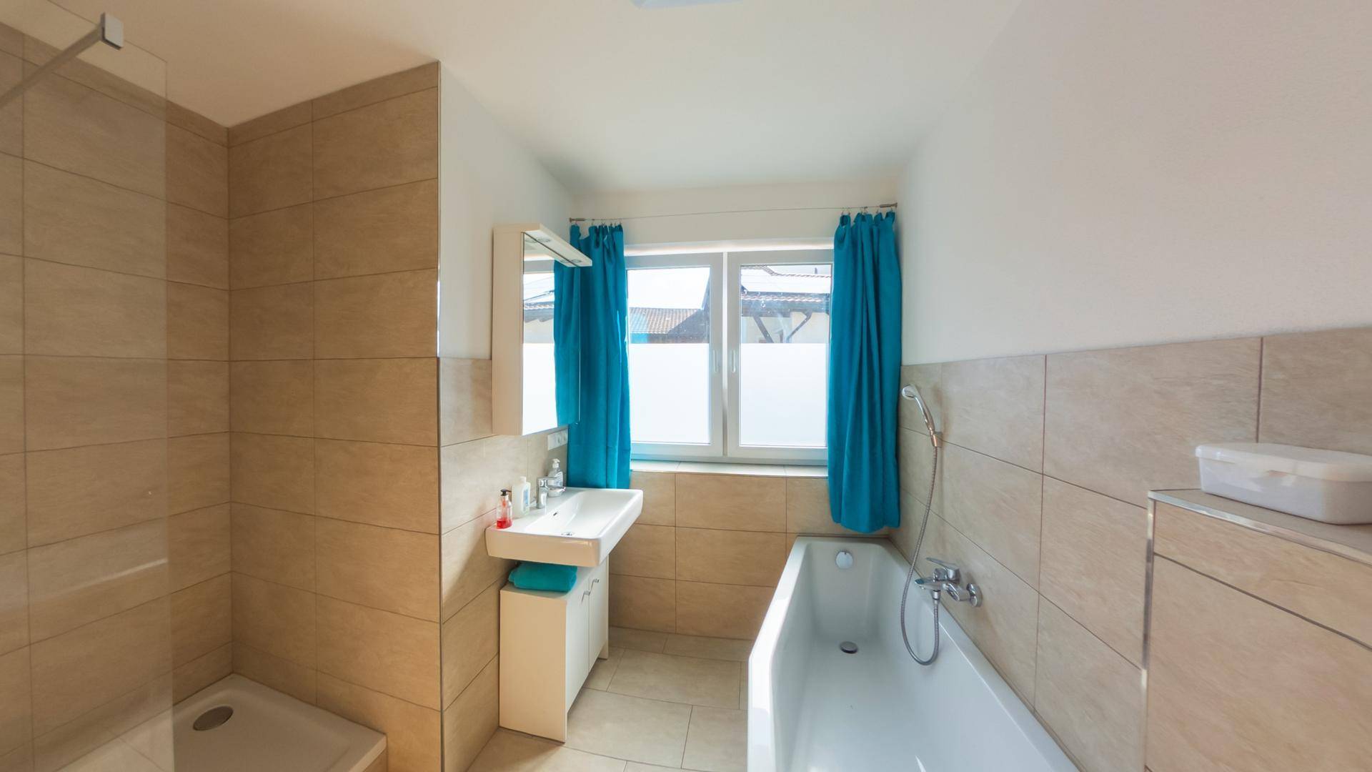 Modernes Badezimmer mit Badewanne, Waschtisch und Fenster für natürliche Belüftung.