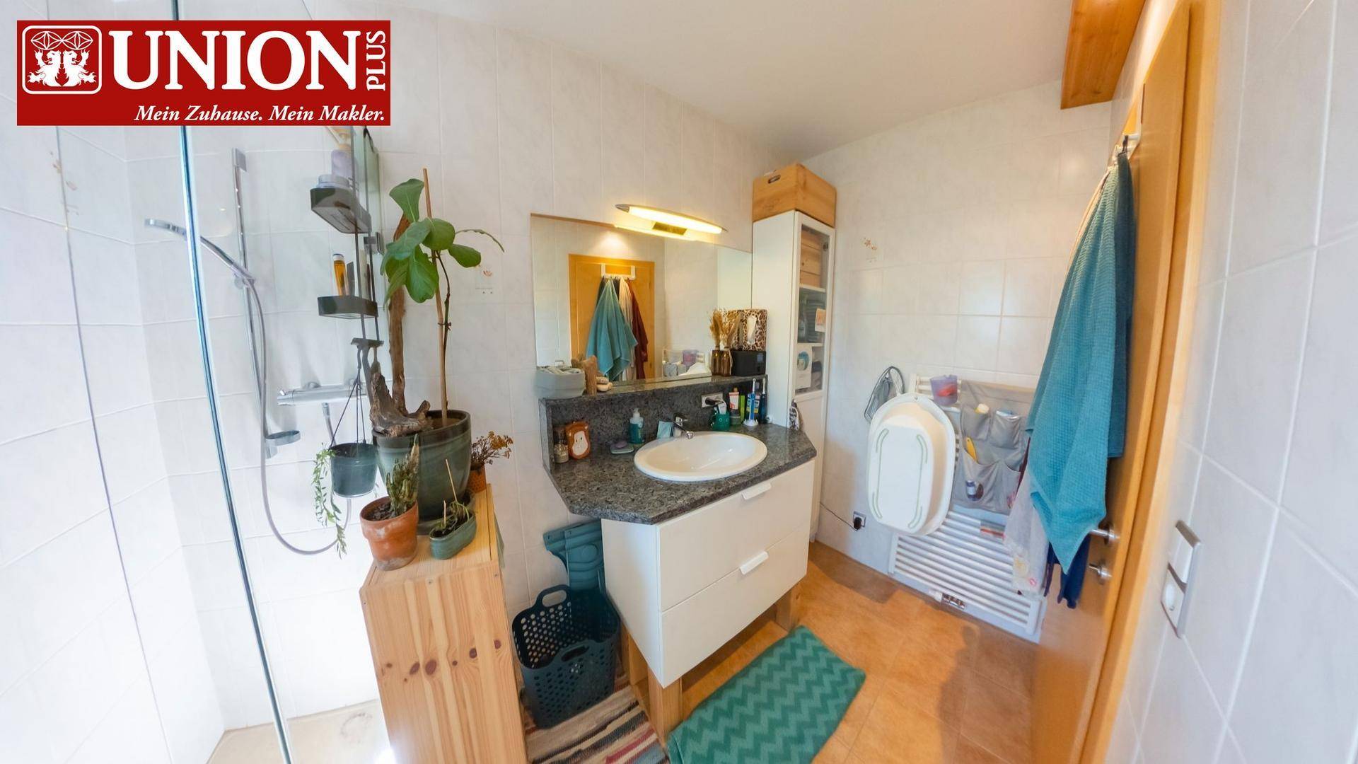 Funktionales Badezimmer mit Dusche, Einzelwaschbecken und hellen Fliesen.