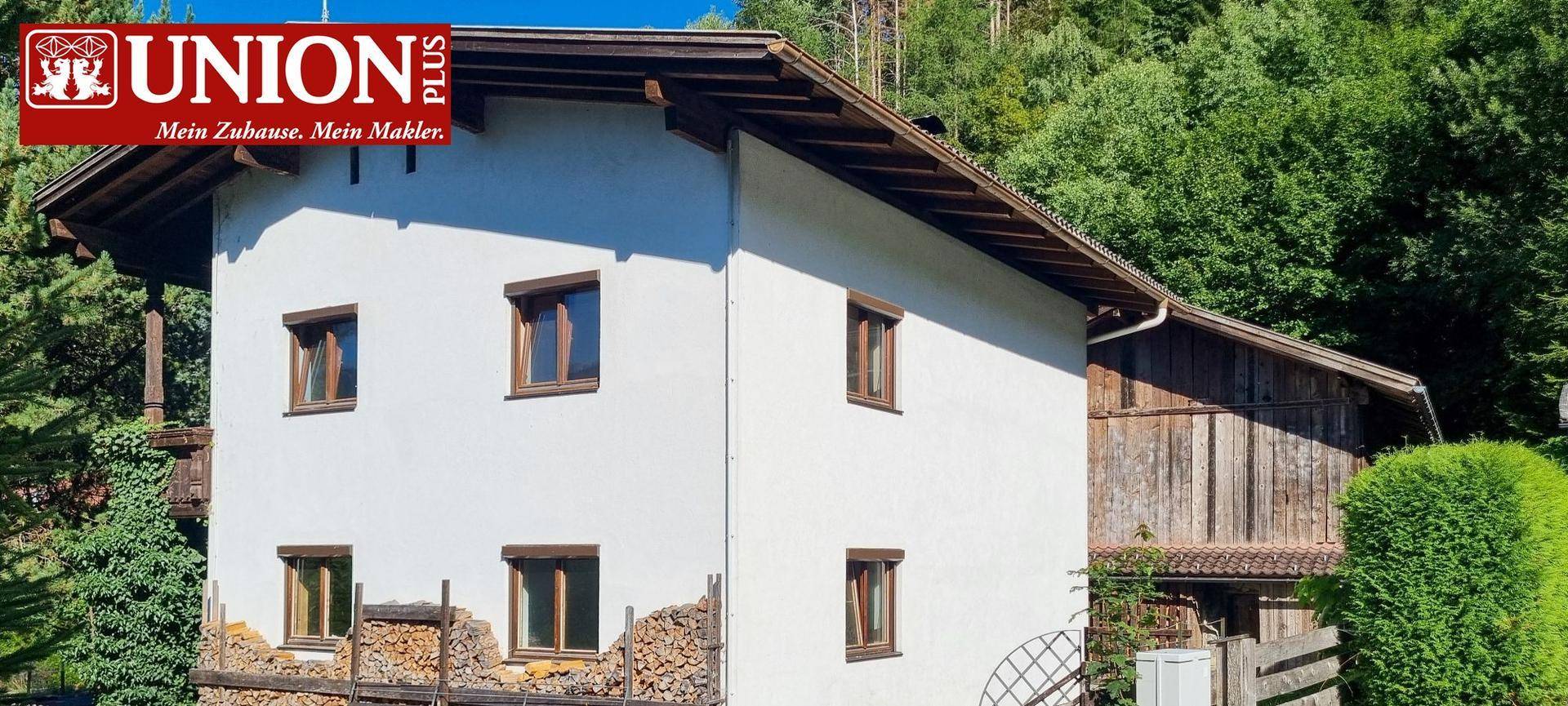 Nahaufnahme des weißen Wohnhauses mit braunen Fensterrahmen und Holzbalken.