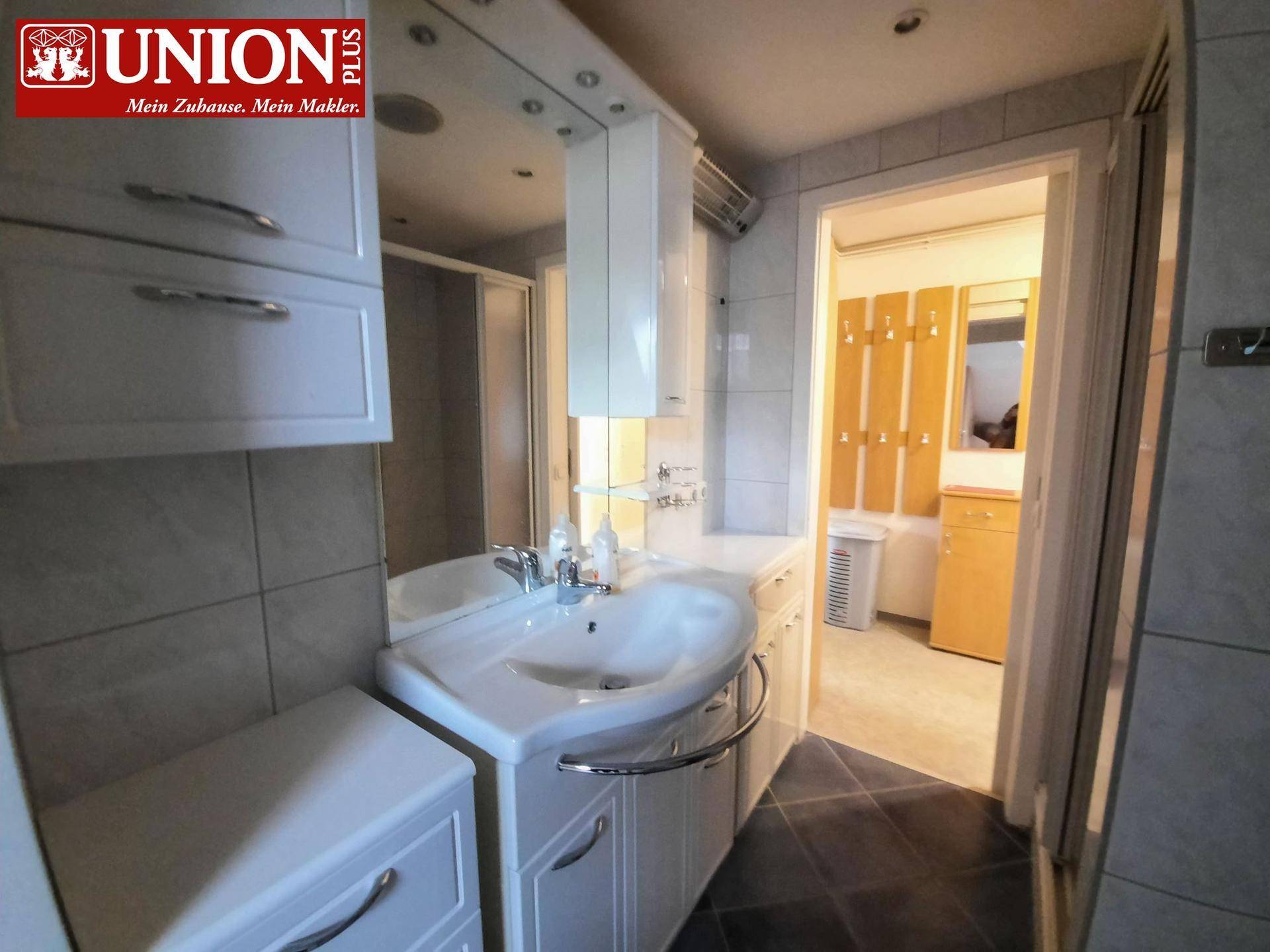 Modernes Badezimmer mit Einzelwaschbecken, Spiegelschrank und Duschkabine.