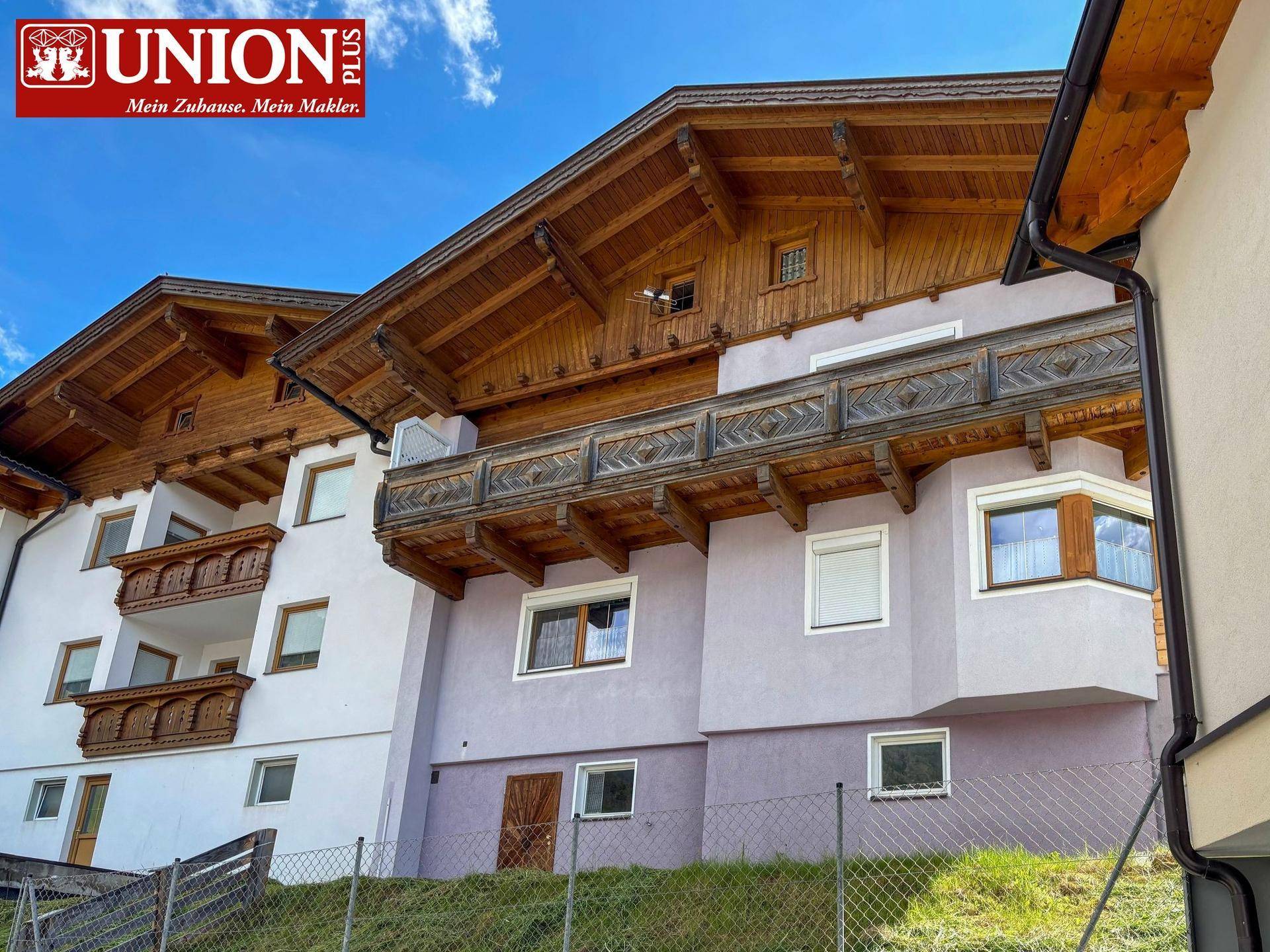 Traditionelle Holzfassade eines Chalets mit mehreren Balkonen und Satteldach.