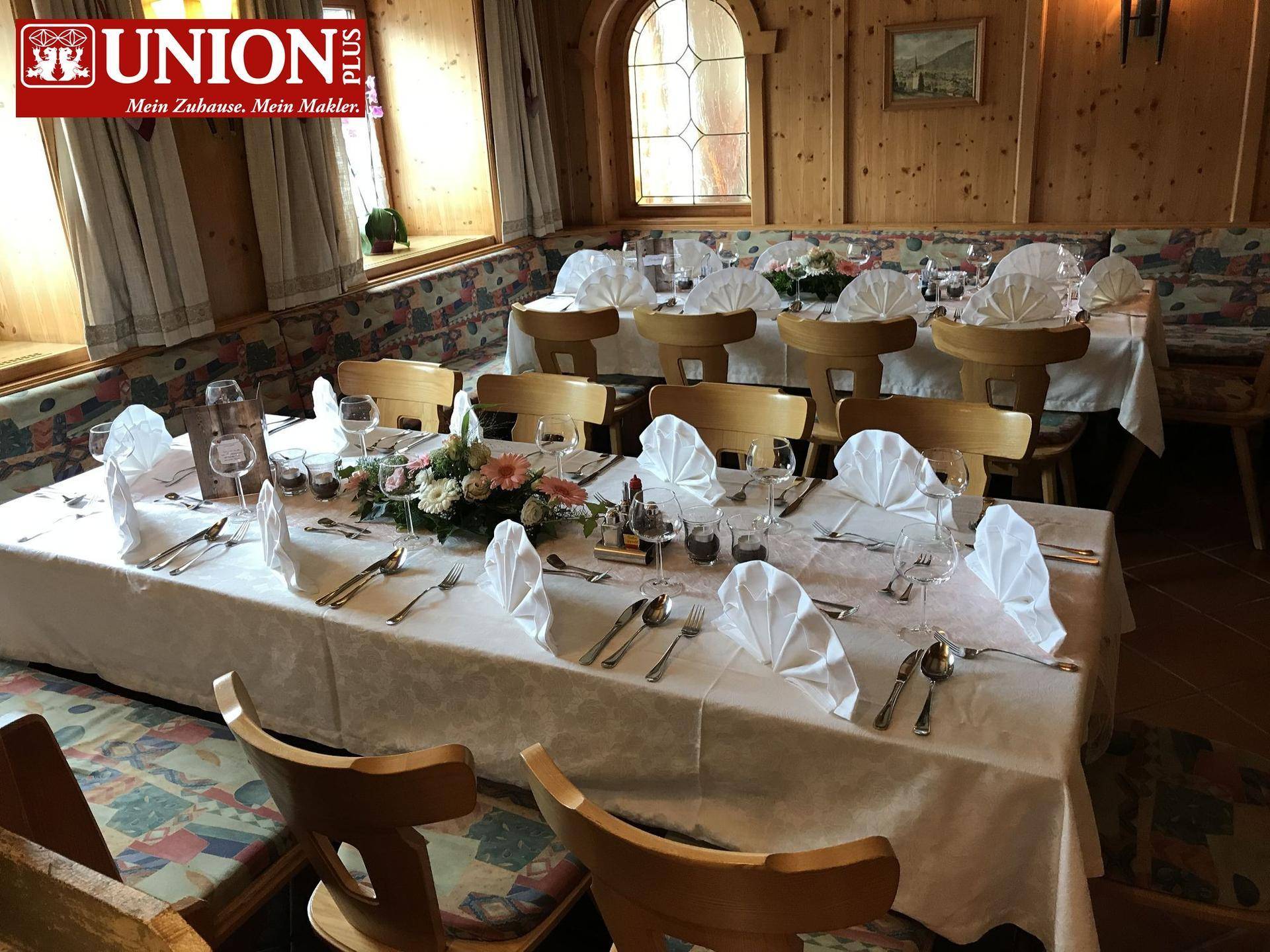 Festlich gedeckter Speisesaal mit traditionellen Holzmöbeln und gepolsterten Bänken.