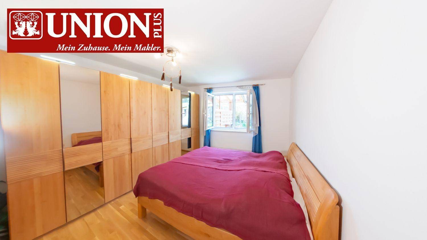 Gemütliches Schlafzimmer mit Holzbett, großem Spiegelschrank und Parkettboden.