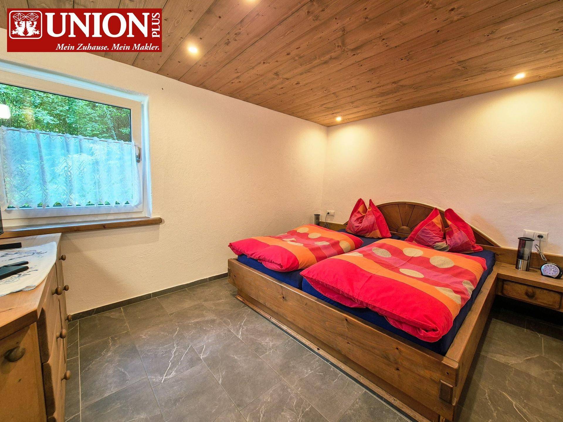 Schlafzimmer mit Holzbett, Holzdecke und Fliesenboden, bietet eine ruhige Atmosphäre.