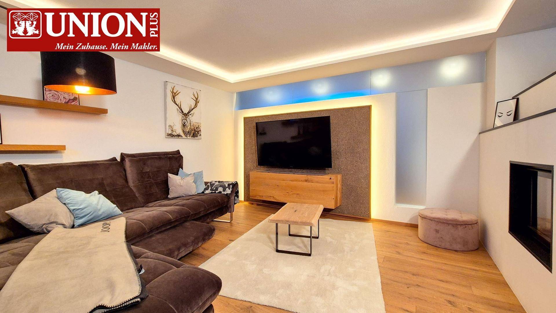 Gemütliches Wohnzimmer mit großem Sofa, modernem TV-Bereich und integriertem Kamin.