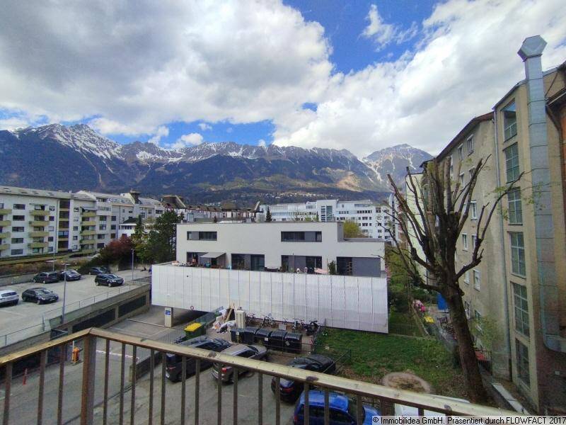 Panoramablick auf die schneebedeckten Berge und die umliegende Stadtbebauung mit modernen Gebäuden.