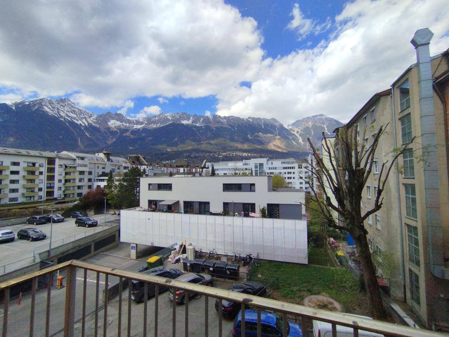 Panoramablick vom Balkon über die Stadt mit schneebedeckten Bergen im Hintergrund.