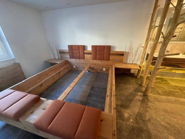 Detailansicht des maßgefertigten Holzbetts mit gepolsterten Elementen und integrierten Nachttischen.