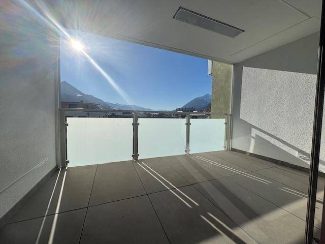 Sonnige Loggia mit moderner Milchglasbrüstung und beeindruckendem Bergblick.