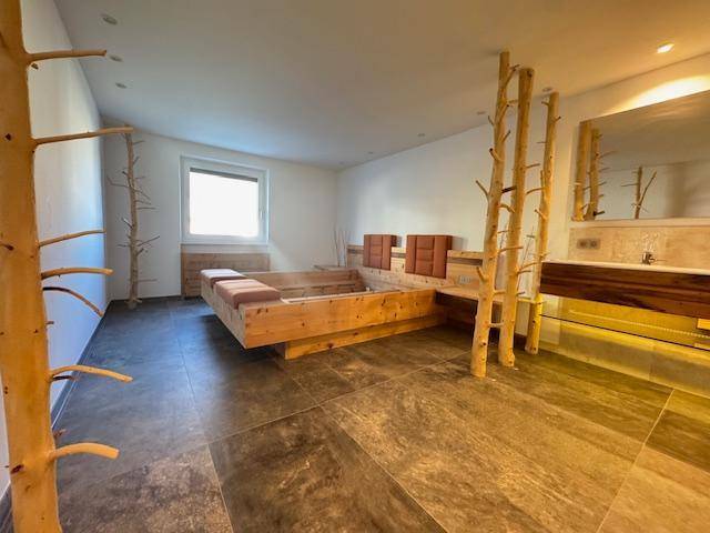 Schlafzimmer mit einzigartigem Holzbettdesign, integriertem Waschbereich und Fliesenboden.