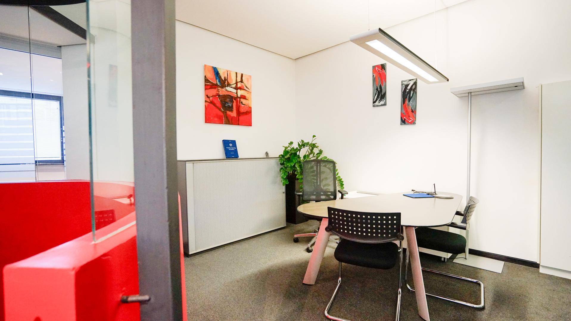Besprechungsraum mit modernem Tisch, Bürostühlen und abstrakten Kunstwerken an der weißen Wand.