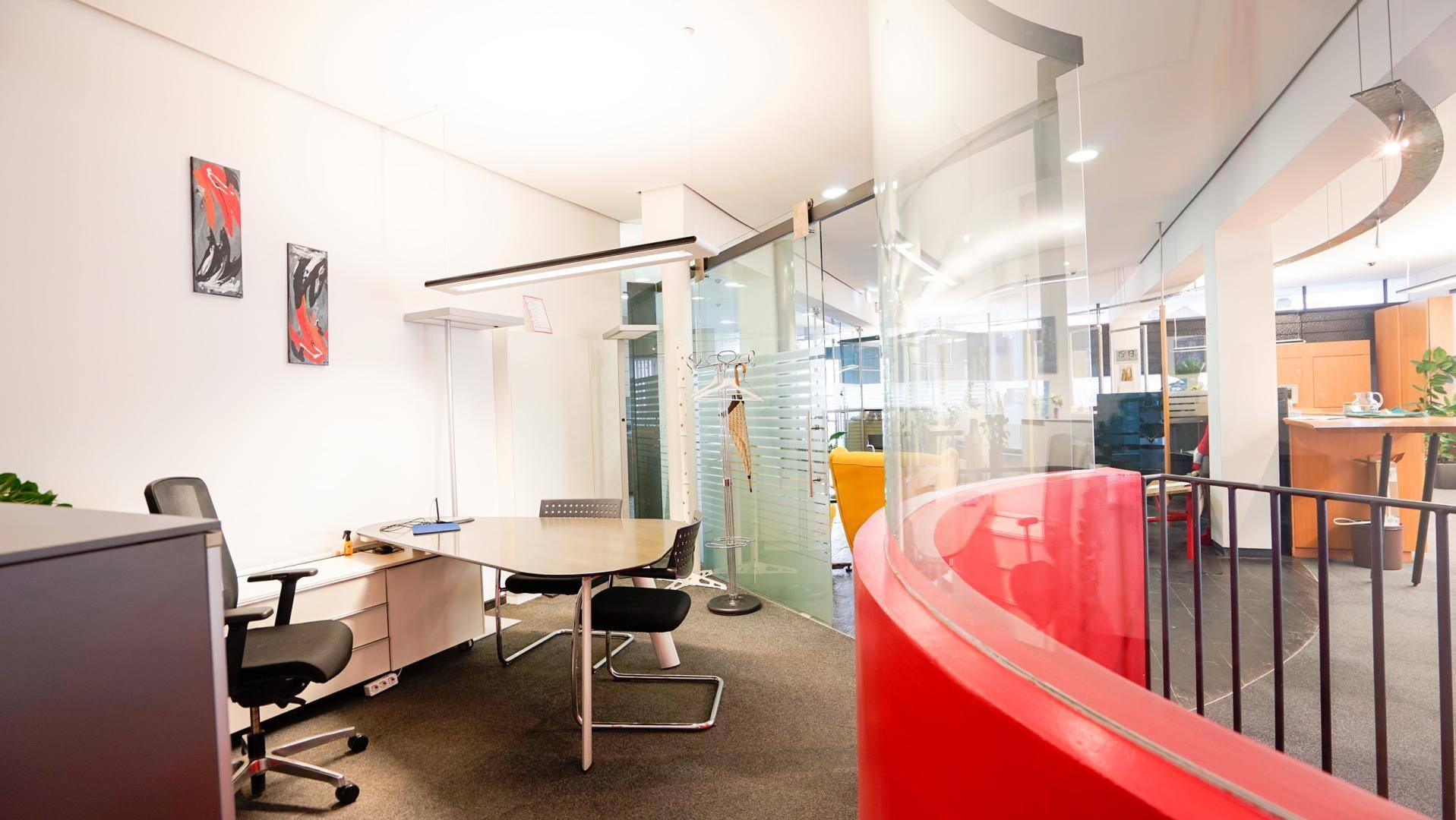 Büro-Arbeitsplatz mit modernem Schreibtisch, Bürostühlen und Blick auf den Empfangsbereich.