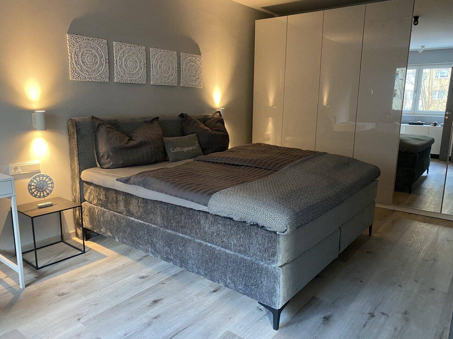 Gemütliches Schlafzimmer mit großem Bett, weißem Kleiderschrank und hellem Laminatboden.