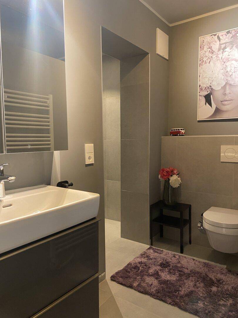 Modernes Badezimmer mit stilvollem Waschbecken, wandhängendem WC und großer Duschkabine.