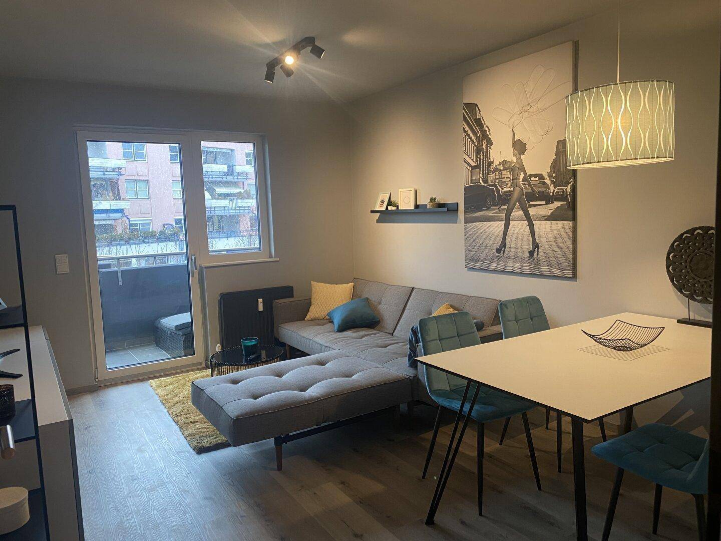 Heller Wohn-Essbereich mit Zugang zum Balkon und modernem Sofa.