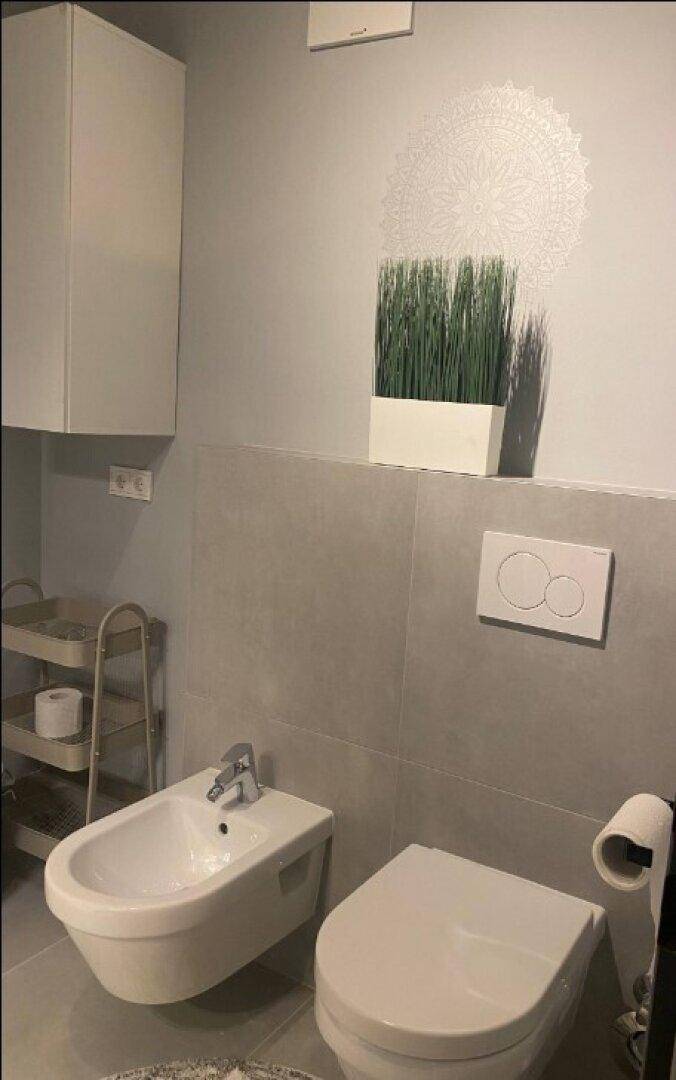 Separates WC mit Bidet, wandhängender Toilette und modernen Fliesen.