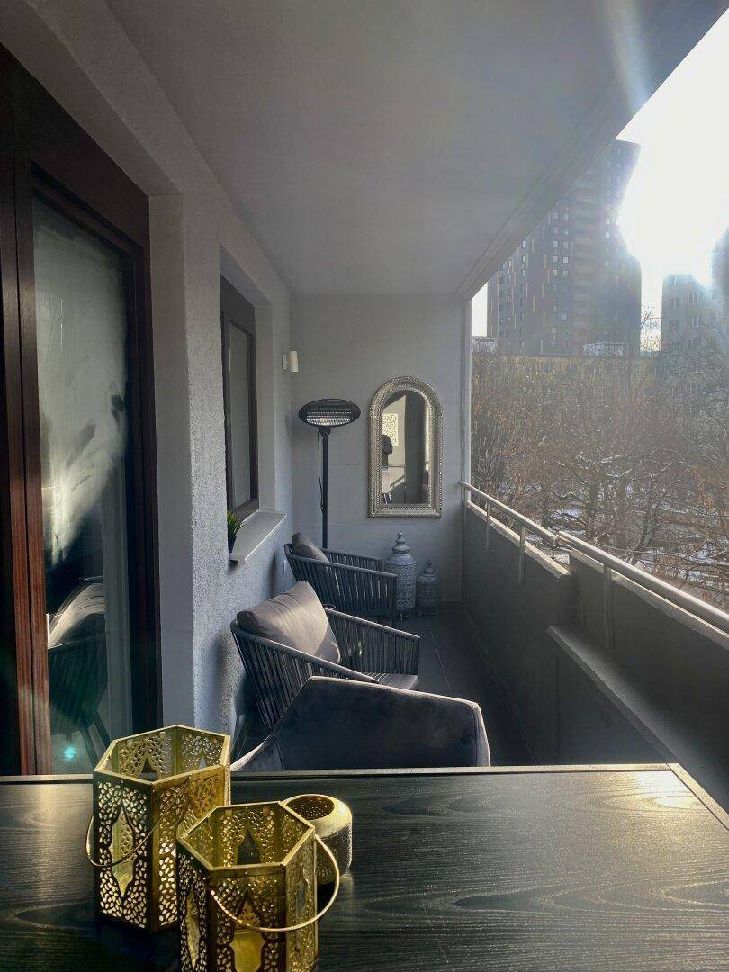 Sonniger Balkon mit bequemen Sitzmöbeln und Blick auf die Stadt.
