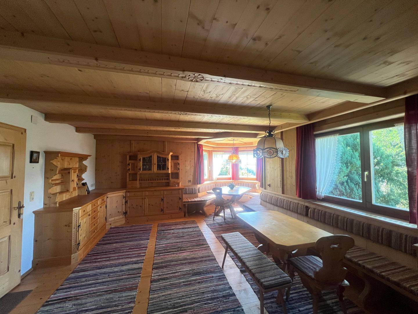 Geräumiger Wohn-Essbereich mit viel Holz, traditionellen Möbeln und großen Fenstern.