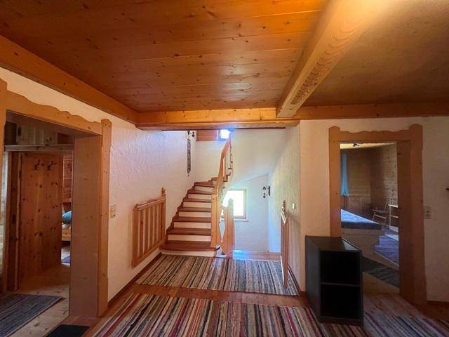 Heller Flur mit Holztreppe und traditionellen Teppichen, der zu den oberen Etagen führt.