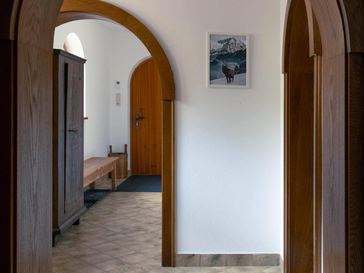 Heller Flur mit rustikalen Holzbögen, Fliesenboden und einer traditionellen Holzbank.