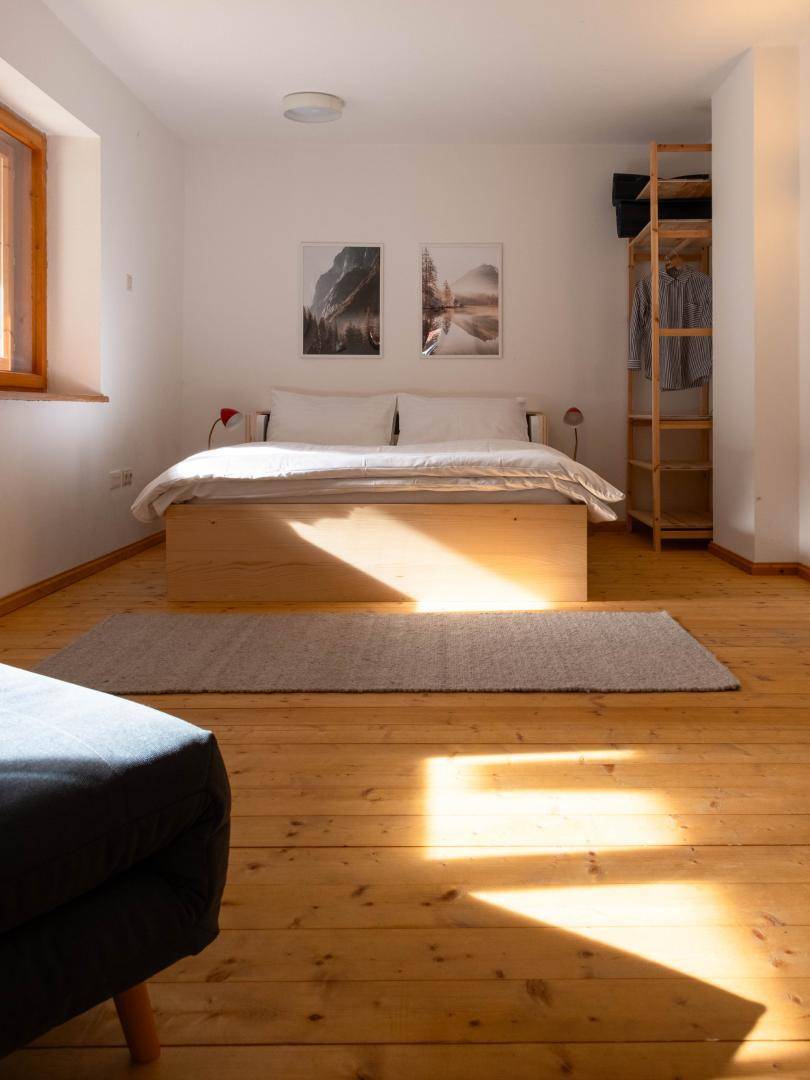 Lichtdurchflutetes Schlafzimmer mit Holzboden, offenem Kleiderschrank und viel Tageslicht.