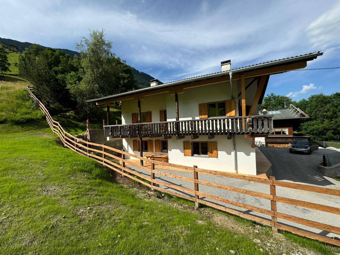Charmantes Haus im Grünen mit Holzbalkon und Blick auf die umliegende Berglandschaft.