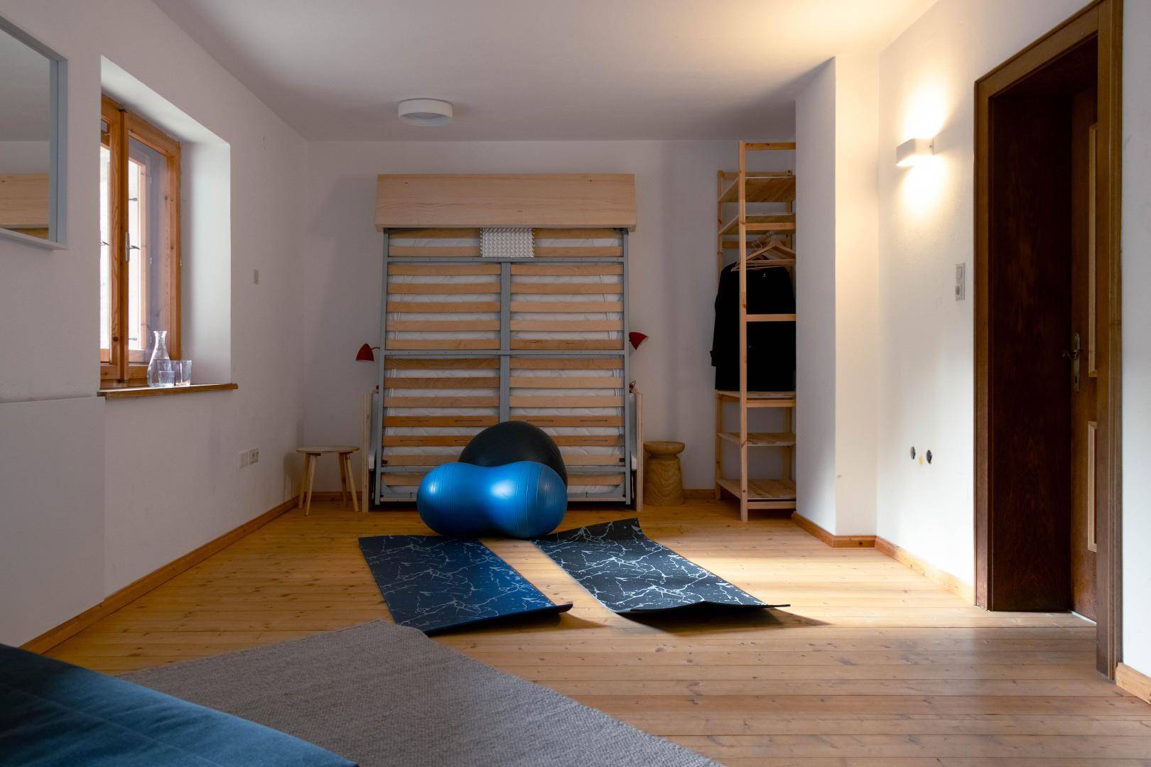 Flexibler Raum mit Klappbett, Holzboden und Sportgeräten für aktive Nutzung.