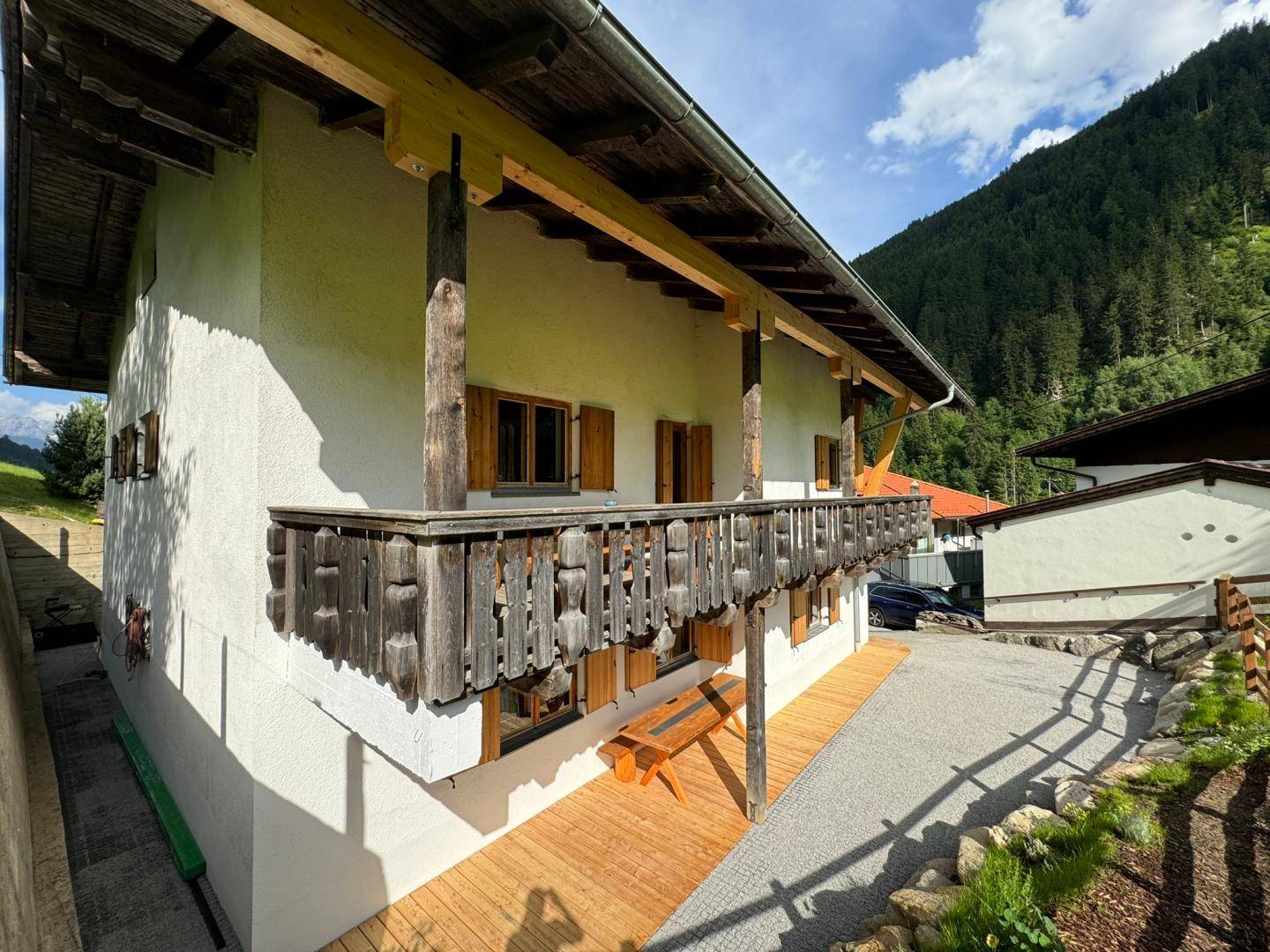 Traditioneller Holzbalcon an der Hausfassade mit rustikalem Geländer und Sitzbank.