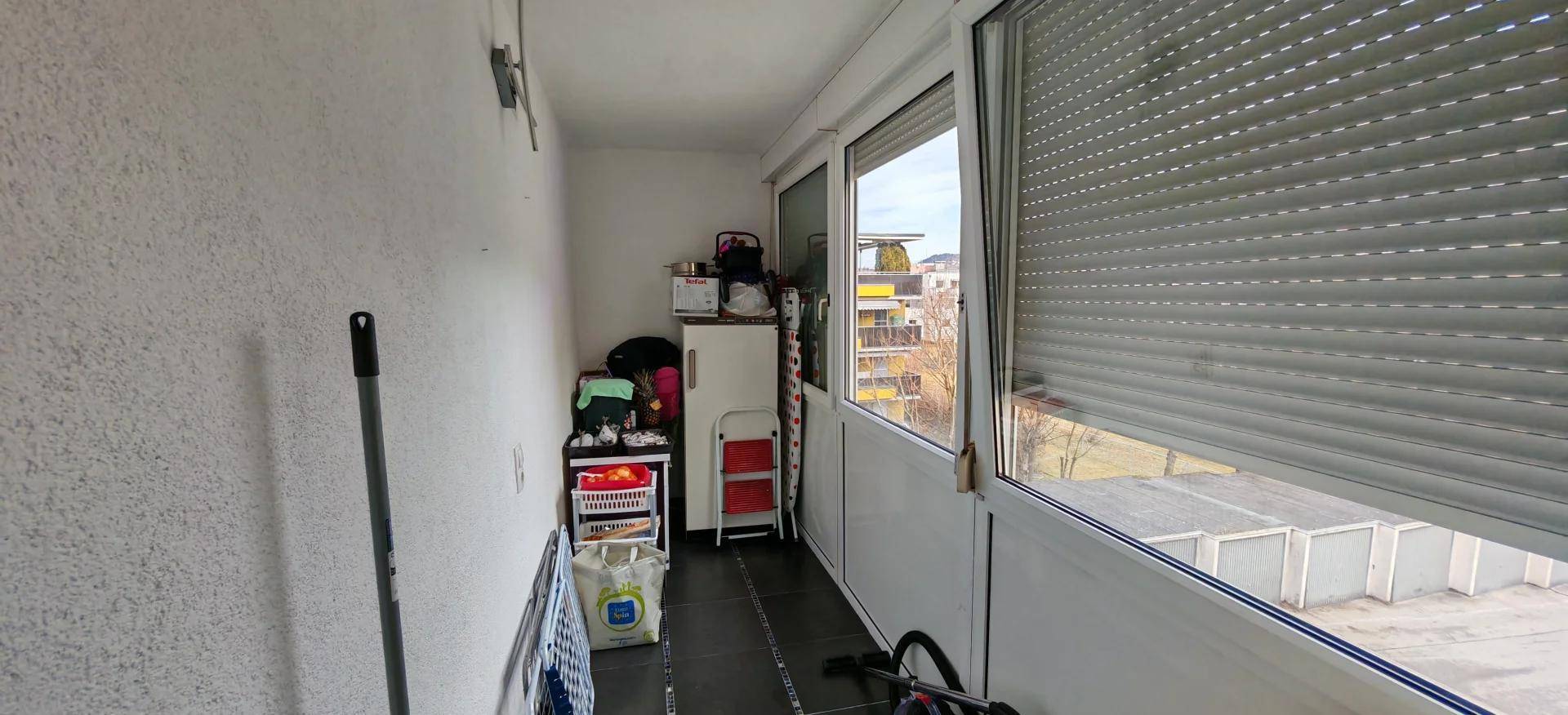 Verglaster Balkon mit Rollläden und Stauraum, bietet zusätzlichen Platz.