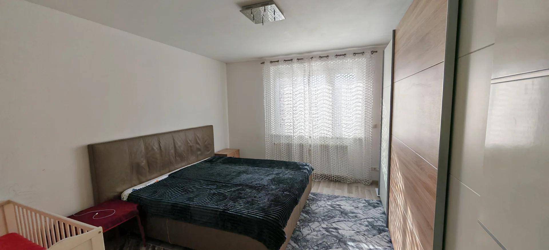 Gemütliches Schlafzimmer mit Doppelbett, Babybett und Holzboden.