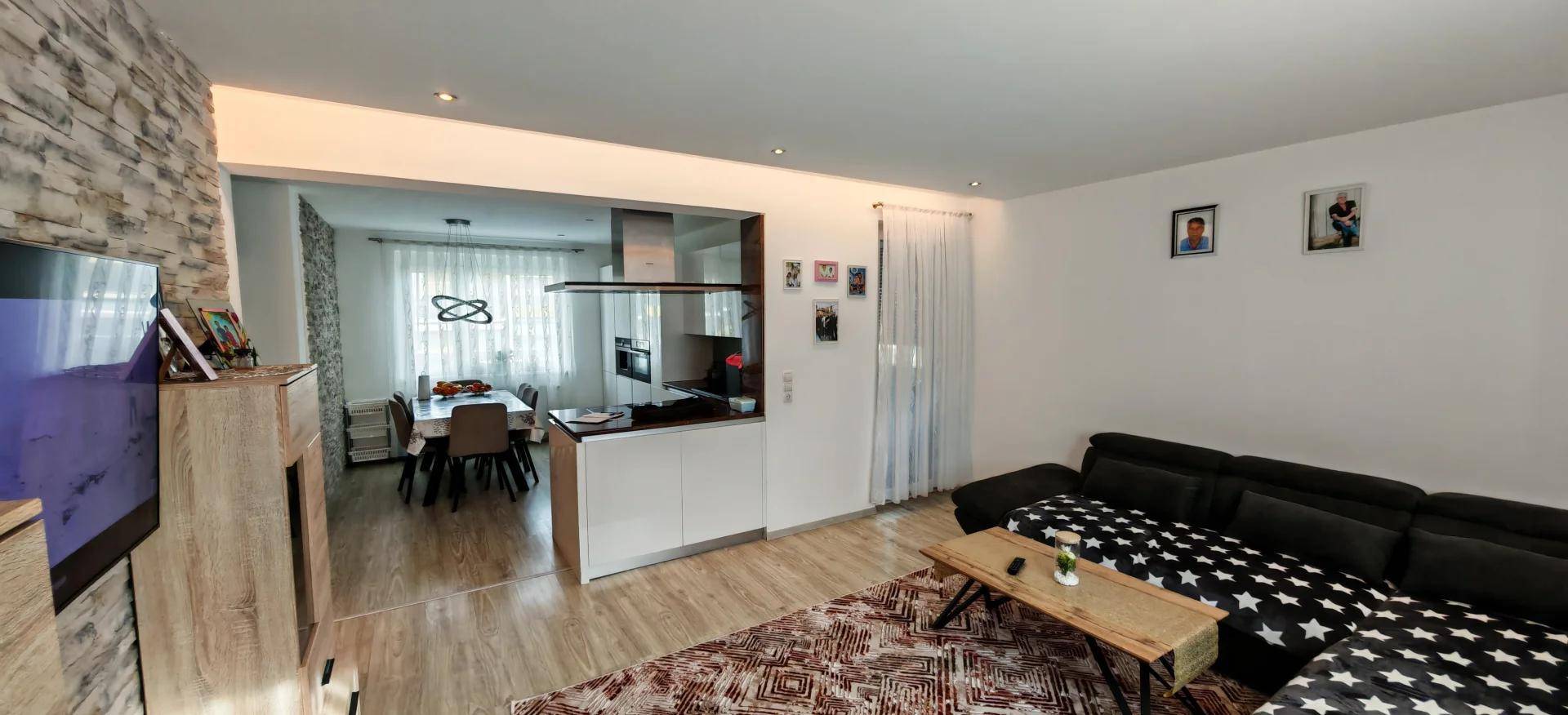 Moderner Wohnbereich mit bequemer Couch, Holzboden und Blick in den Essbereich.